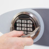 Hand gripping the handle on a phoenix fortress 1185 security safe electronic lock keypad