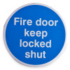 Round self adhesive metal sign with fire door keep locked shut text in white on blue background front view