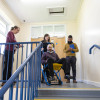 Person in chair going down stairs as part of evacuation chair operator training with instructors nearby