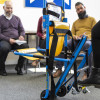 Students watching evacuation chair operator training with a blue and yellow evacuation chair in the foreground