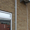 Wall-mounted closed Saffold Fold Out Fire Escape Ladder installed beside a window on a brick building