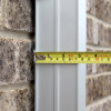 Close up of a tape measure showing the closed width of the Saffold Fold Out Fire Escape Ladder against a brick wall