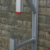 Close-up of the Saffold Fold Out Fire Escape Ladder Join showing the metal frame and connection parts against a brick wall