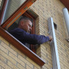 Man mounting Saffold Fold Out Fire Escape Ladder Man Release Pin on brick wall outside window