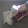 Hand removing a 3 in 1 led emergency torch night light from its wall charger with light switched on
