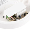 A circular casing containing a circuit board with resistors, capacitors, and a relay, partially covered by a white plastic shield.