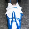 person secured under white cushions on a blue spectrum healthcare ski sled on a tiled floor
