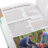 Close up of an open st john ambulance first aid manual showing text and a photo of two people assisting a casualty outdoors