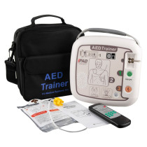 Complete AED training kit laid out, including the AED Trainer device, black carrying case, remote control, electrode pads, and instruction materials