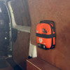 An orange AED unit is mounted on a wooden wall inside a van. The case features AED markings, including a heart with a lightning bolt, and is secured within the vehicle’s neatly panelled interior.