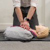 Person practising chest compressions on a laerdal little anne qcpr light training manikin on the floor