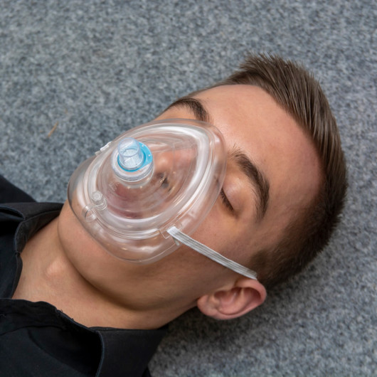 Front view of a person wearing a St John Ambulance rescue mask over the nose and mouth
