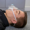 Side view of a person lying down wearing a st john ambulance rescue mask with a clear face cover and strap