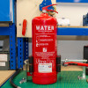 Close front view of ultrafire extinguisher servicing clamp holding a red fire extinguisher on a workbench