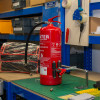Red fire extinguisher secured on an engineer bench with an ultrafire extinguisher servicing clamp attached