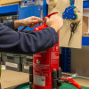 Hands inspecting the handle of an ultrafire extinguisher servicing clamp in a workshop setting