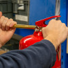 Close-up of hands using an ultrafire extinguisher servicing clamp to pressurise a red fire extinguisher