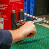 Close up of a hand releasing clamp on an ultrafire extinguisher servicing clamp attached to a red extinguisher
