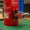 Ultrafire extinguisher servicing clamp attached to a red extinguisher with a pressure gauge being checked