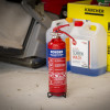 Ultrafire 1kg powder fire extinguisher standing on a workshop floor with containers in the background