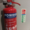 Ultrafire powder fire extinguisher 2kg shown upright fixed to a wall with safety instructions visible nearby