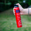 Hand holding the ultrafire 600g powder extinguisher showing the right side of the product against a blurred outdoor background