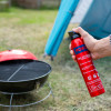 Hand holding an Ultrafire 600g powder extinguisher near a small barbecue on grass with a tent in the background