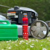 Ultrafire 600g powder extinguisher standing on grass outside next to a green petrol can and a lawnmower wheel