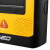 Close‑up of a yellow AED showing part of the screen area, a rectangular button, an orange shock button with a lightning symbol, and vented casing.