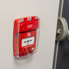 Red sigma smart+guard call point cover flush mounted on wall with clear protective lid and visible instructions insitu