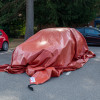 bridgehill single use car fire blanket partially covering a car parked outdoors with trees in the background