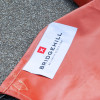 Close-up of a white tag on a Bridgehill single use car fire blanket with the brand name and logo on an orange fabric background