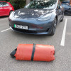 Rolled up car fire blanket for electric vehicles bridgehill on the ground in front of a parked dark grey car