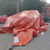 Car fire blanket for electric vehicles Bridgehill shown in use covering a parked car in a parking lot