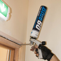 Blue 60 intumescent foam is applied in the gap between fire door frame and wall to stop fire spreading through the gap