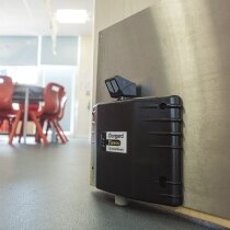 Black Dorgard SmartSound fire door retainer installed on a canteen door